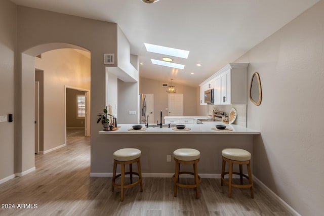 kitchen with white cabinetry, a kitchen bar, kitchen peninsula, and appliances with stainless steel finishes