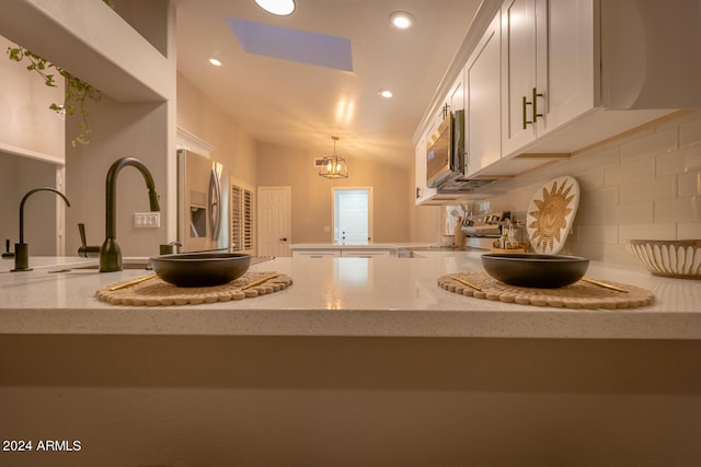 kitchen featuring an inviting chandelier, hanging light fixtures, light stone countertops, tasteful backsplash, and stainless steel appliances