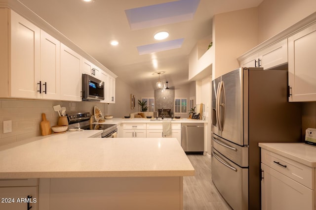 kitchen with kitchen peninsula, white cabinetry, sink, and stainless steel appliances