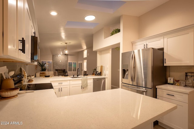 kitchen with tasteful backsplash, kitchen peninsula, sink, and appliances with stainless steel finishes