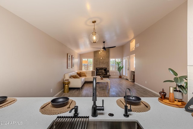 kitchen with dark hardwood / wood-style flooring, ceiling fan, decorative light fixtures, a fireplace, and lofted ceiling