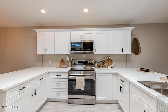 kitchen featuring backsplash, kitchen peninsula, white cabinetry, and stainless steel appliances