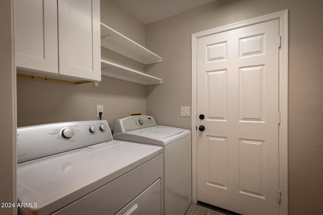 clothes washing area featuring cabinets and separate washer and dryer