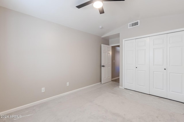 unfurnished bedroom featuring ceiling fan, a closet, light carpet, and vaulted ceiling