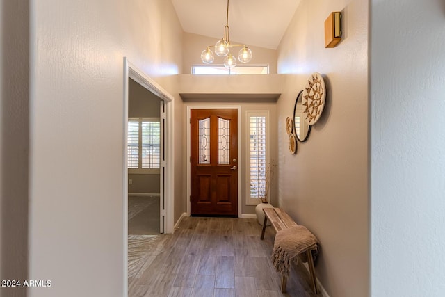 foyer featuring hardwood / wood-style flooring, an inviting chandelier, and vaulted ceiling