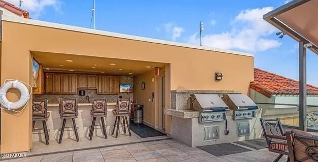 view of patio with an outdoor kitchen, exterior bar, and area for grilling