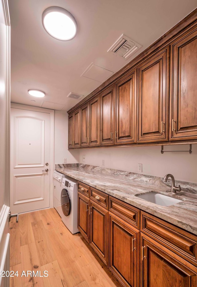 laundry room featuring cabinets, sink, light hardwood / wood-style floors, and washer / clothes dryer