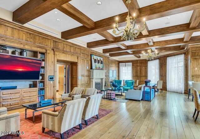 living room with wood walls, hardwood / wood-style flooring, coffered ceiling, beamed ceiling, and a notable chandelier