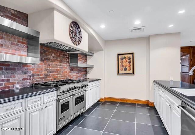 kitchen with appliances with stainless steel finishes, sink, dark tile patterned floors, white cabinets, and decorative backsplash