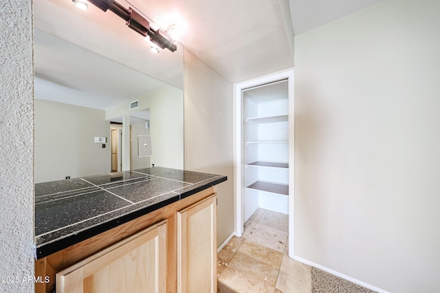 kitchen with tile countertops, baseboards, visible vents, and light brown cabinetry