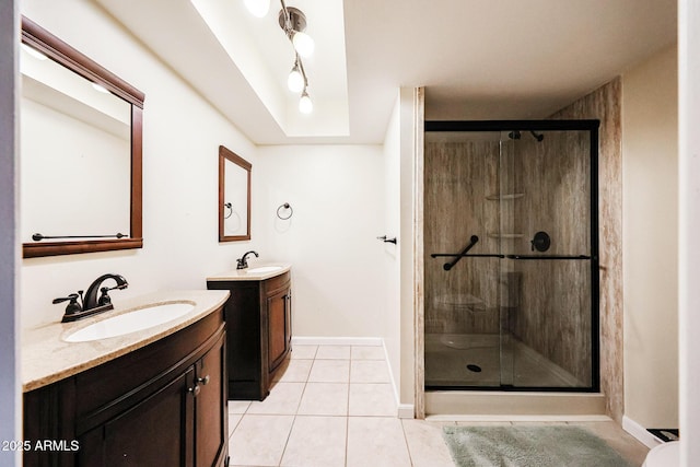 bathroom with tile patterned flooring, two vanities, a stall shower, and a sink