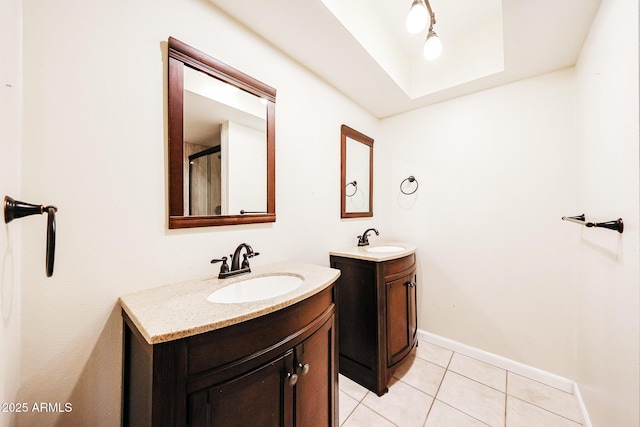 bathroom with tile patterned flooring, two vanities, baseboards, and a sink