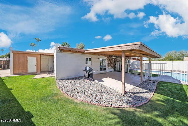 rear view of house featuring a fenced in pool, a fenced backyard, a yard, an outbuilding, and a patio