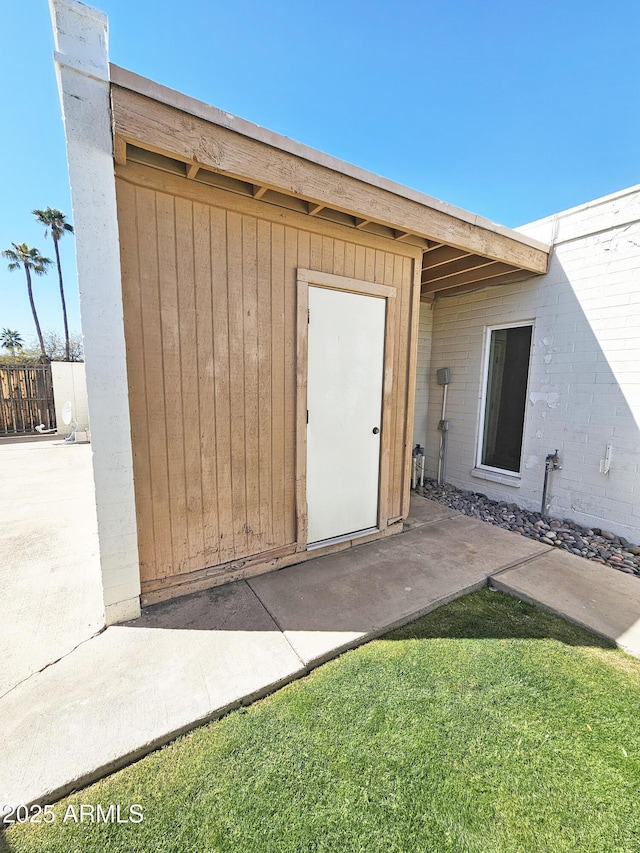 view of exterior entry featuring a yard and brick siding