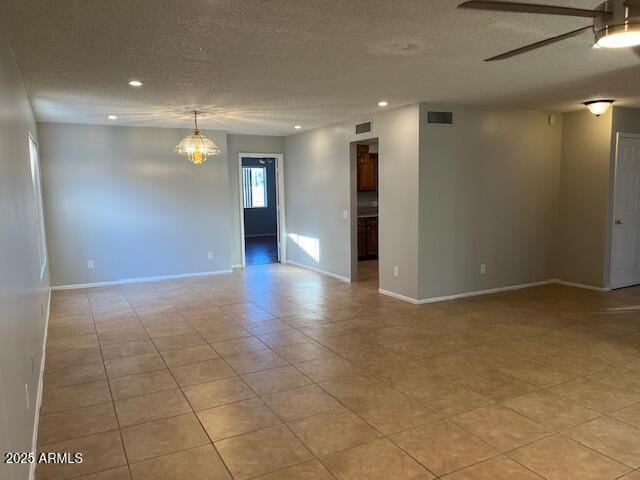 spare room featuring ceiling fan with notable chandelier, light tile patterned flooring, and a textured ceiling