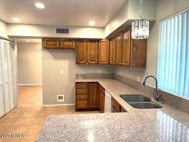 kitchen featuring light stone countertops, a chandelier, decorative light fixtures, light tile patterned floors, and sink