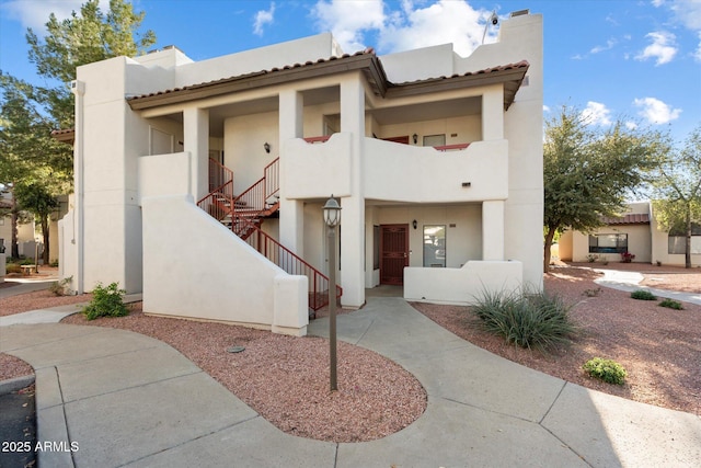 adobe home featuring stucco siding, stairs, and a chimney