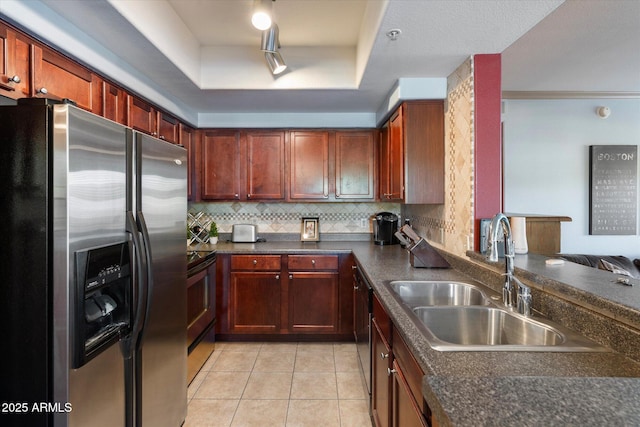 kitchen featuring decorative backsplash, dark countertops, a raised ceiling, appliances with stainless steel finishes, and a sink