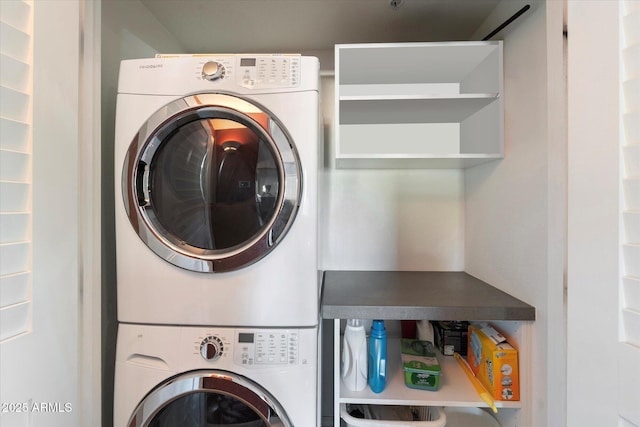 clothes washing area featuring stacked washer and clothes dryer and laundry area