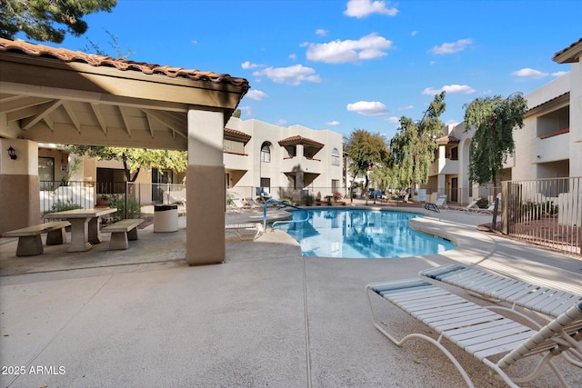 community pool with a residential view, fence, and a patio