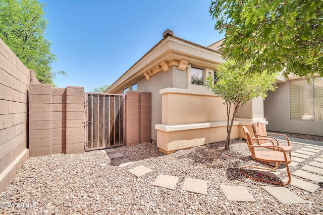 view of property exterior with a gate, fence, and stucco siding