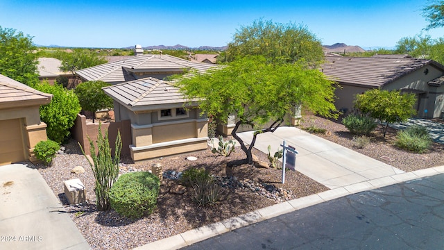 view of front of house featuring fence, a tile roof, a mountain view, and stucco siding