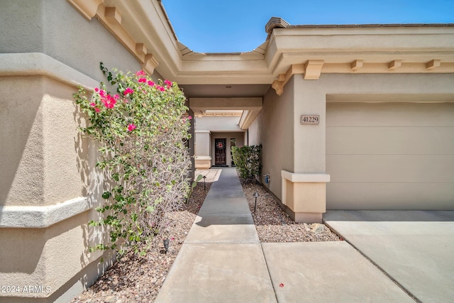 entrance to property featuring a garage and stucco siding