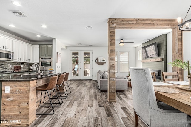 3109 N Black Rock Rd, Buckeye, AZ 85396 - kitchen with appliances with stainless steel finishes, a sink, a breakfast bar area, light wood-style floors, and backsplash