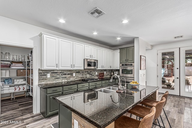 3109 N Black Rock Rd, Buckeye, AZ 85396 - kitchen with a sink, stainless steel appliances, a kitchen bar, light wood-style flooring, and backsplash