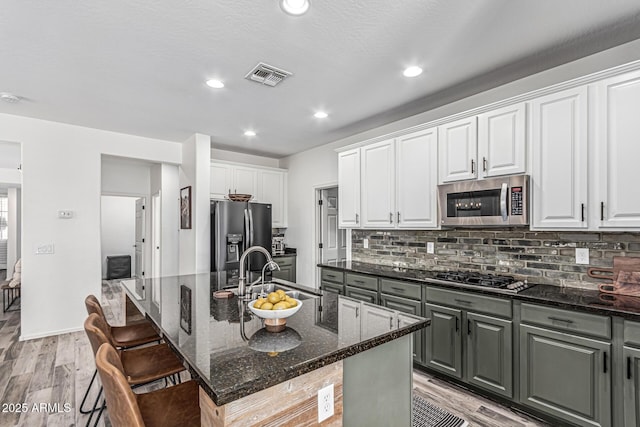 3109 N Black Rock Rd, Buckeye, AZ 85396 - kitchen featuring stainless steel appliances, a sink, light wood-style flooring, dark stone countertops, and backsplash