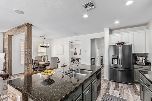 3109 N Black Rock Rd, Buckeye, AZ 85396 - kitchen featuring stainless steel fridge with ice dispenser, a sink, white cabinetry, a kitchen island with sink, and dark stone countertops