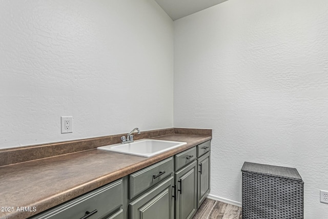3109 N Black Rock Rd, Buckeye, AZ 85396 - laundry area with a sink, light wood finished floors, a textured wall, and baseboards