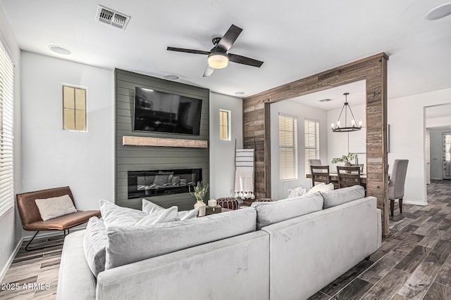 3109 N Black Rock Rd, Buckeye, AZ 85396 - living room featuring dark wood-type flooring, baseboards, a fireplace, a chandelier, and wood walls