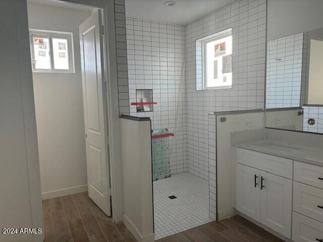 bathroom featuring tiled shower, vanity, and a healthy amount of sunlight