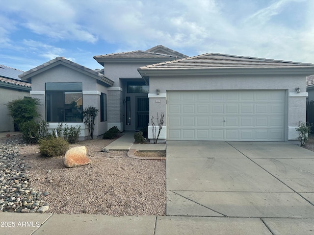 view of front facade with concrete driveway, stucco siding, a tile roof, and a garage