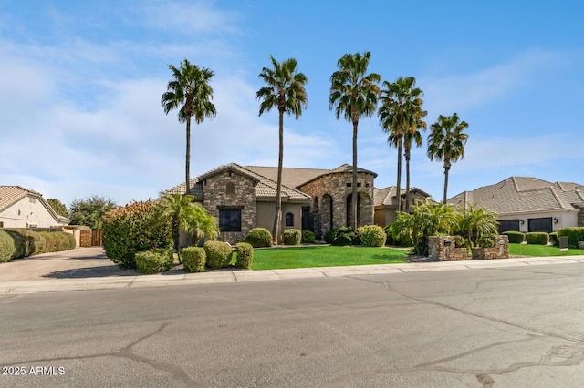 view of front of house featuring stone siding, a front yard, and stucco siding