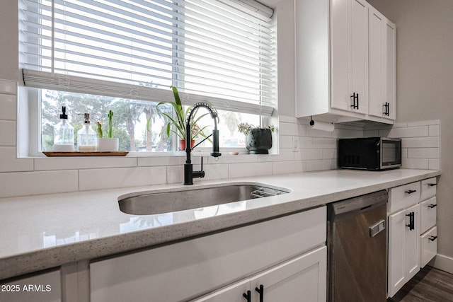 kitchen with black microwave, a sink, white cabinets, dishwasher, and tasteful backsplash