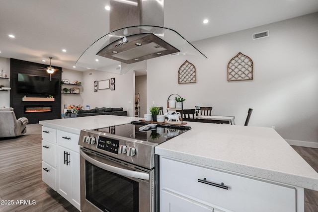 kitchen with visible vents, a fireplace, stainless steel electric stove, and open floor plan