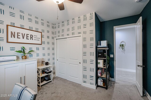 interior space featuring a ceiling fan, light colored carpet, and baseboards