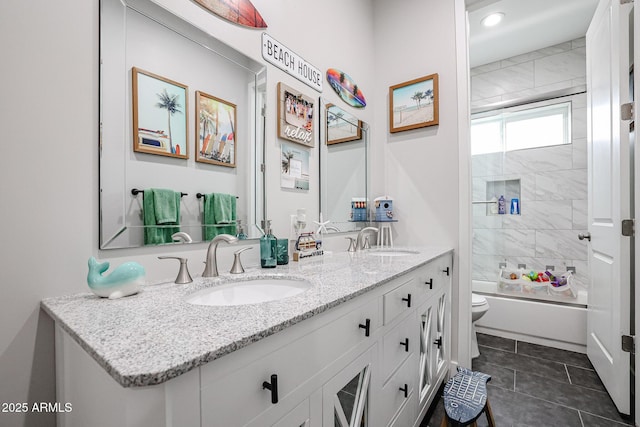 bathroom featuring double vanity, shower / bath combination with glass door, a sink, and toilet