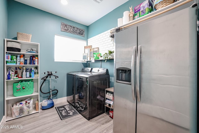 clothes washing area featuring laundry area, washing machine and dryer, baseboards, and wood finished floors