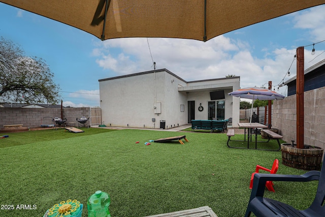 back of house featuring a fenced backyard, a yard, and stucco siding