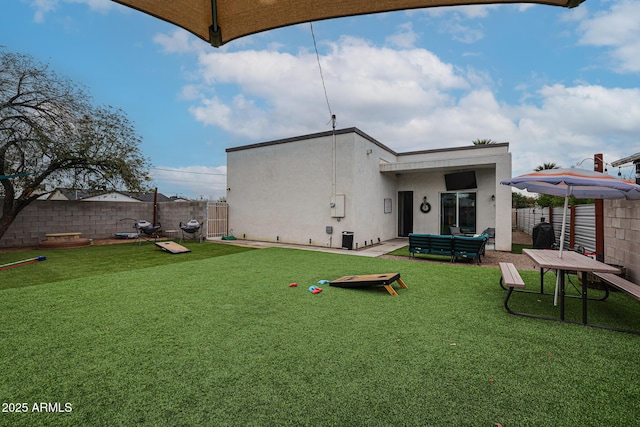 rear view of house featuring a fenced backyard, a yard, and stucco siding