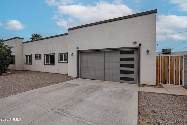 view of front of home featuring driveway, an attached garage, fence, and stucco siding