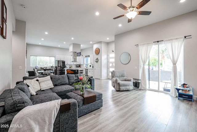 living room featuring recessed lighting, light wood-type flooring, a ceiling fan, and a healthy amount of sunlight