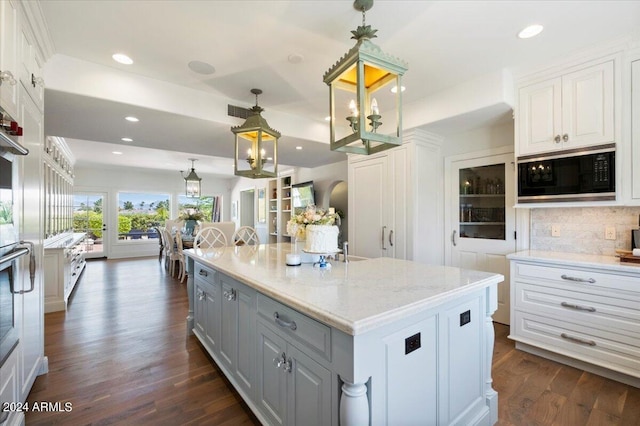 kitchen featuring white cabinetry, black microwave, pendant lighting, a center island, and dark hardwood / wood-style floors