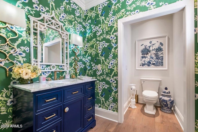 bathroom with vanity, crown molding, hardwood / wood-style floors, and toilet