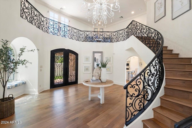 entryway featuring an inviting chandelier, a towering ceiling, hardwood / wood-style flooring, and a healthy amount of sunlight