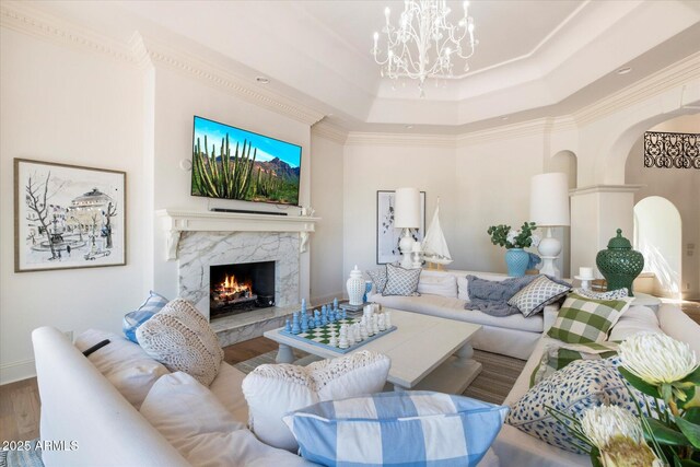 living room featuring an inviting chandelier, a tray ceiling, crown molding, and hardwood / wood-style floors