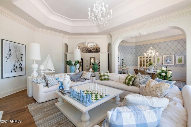 living room featuring a chandelier, a raised ceiling, hardwood / wood-style floors, and crown molding